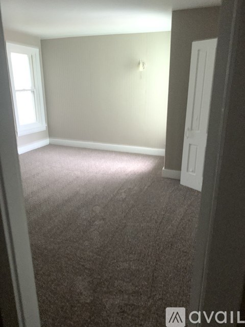 A carpeted room with a door and a window.