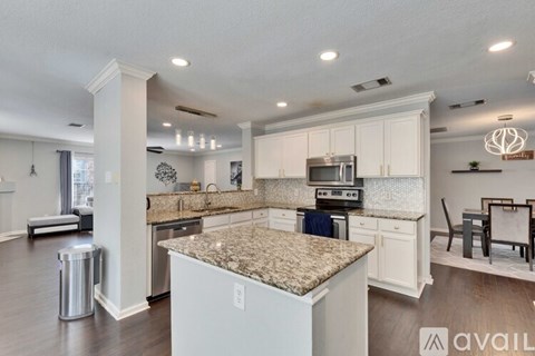 A kitchen with granite countertops and white cabinets.
