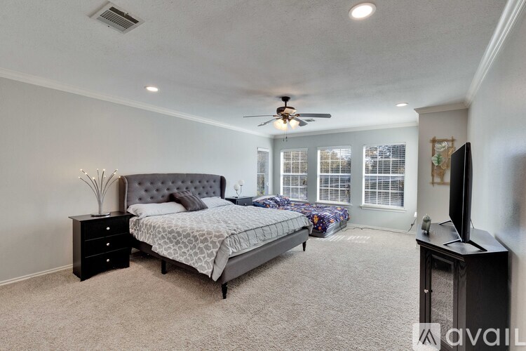 A bedroom with a bed, dresser, and television.
