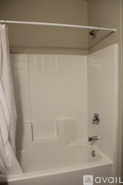 A white bathroom with a white tub and a white shower curtain.
