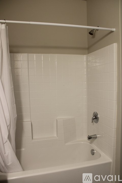 A white bathroom with a white tub and a white shower curtain.