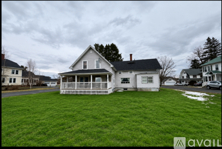 A house with a white porch and a black roof is in the image.