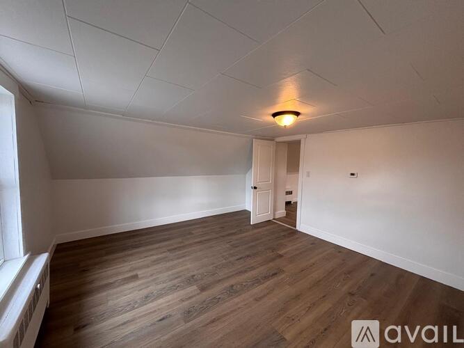 A room with wooden flooring and a window on the left side.