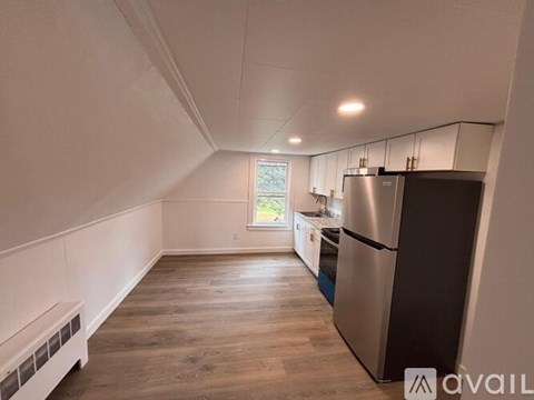 A kitchen with a stainless steel refrigerator and wooden flooring.