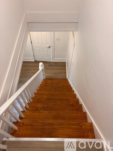 A wooden staircase with white railings leads to a white door.