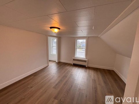 A room with wooden floors and a window with a view of a building outside.