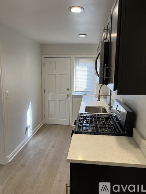 A kitchen with a black stove top oven and a white door in the background.