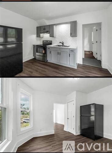 A black refrigerator in a kitchen with white cabinets and a window.