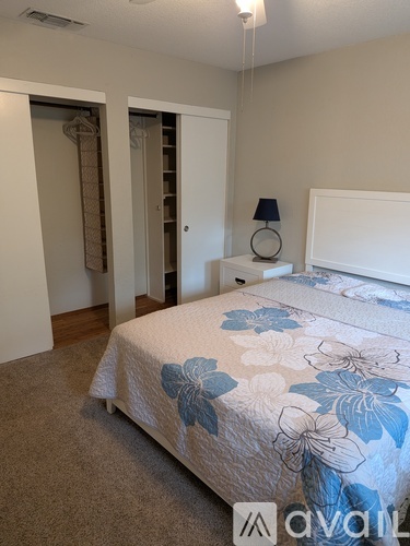 A bedroom with a bed, nightstand, and lamp.