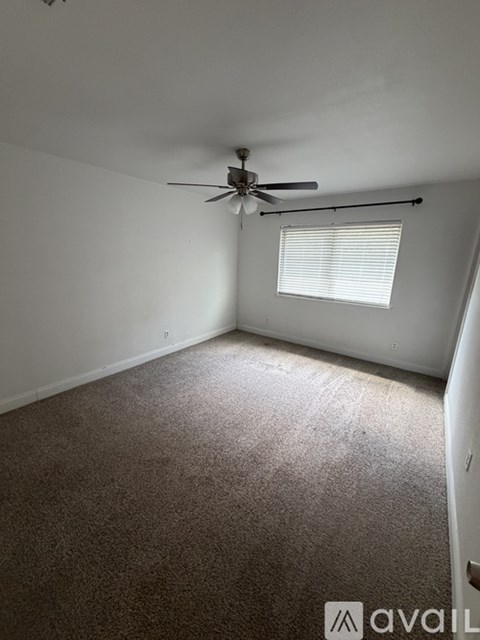 A room with a ceiling fan and a window with blinds.