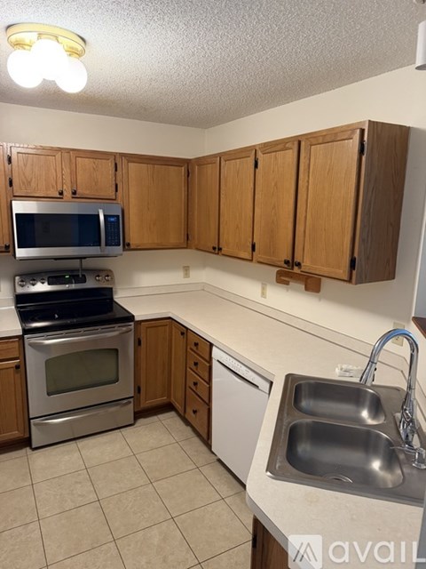 A kitchen with wooden cabinets and a stainless steel sink.