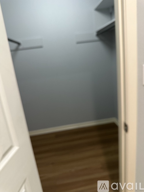 A white door is open to a room with a wooden floor and a wall.