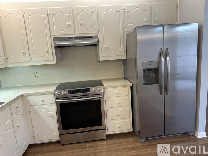 A kitchen with white cabinets and a stainless steel refrigerator.