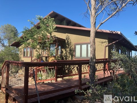 A house with a deck and trees in front.