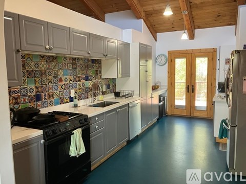 A kitchen with a black stove top oven and a tiled backsplash.