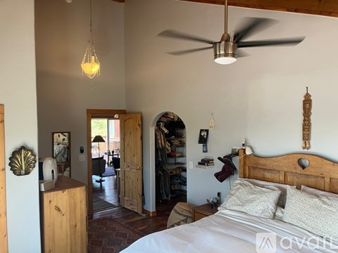 A bedroom with a bed, a dresser, and a ceiling fan.