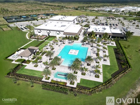 An aerial view of a resort with a swimming pool and palm trees.