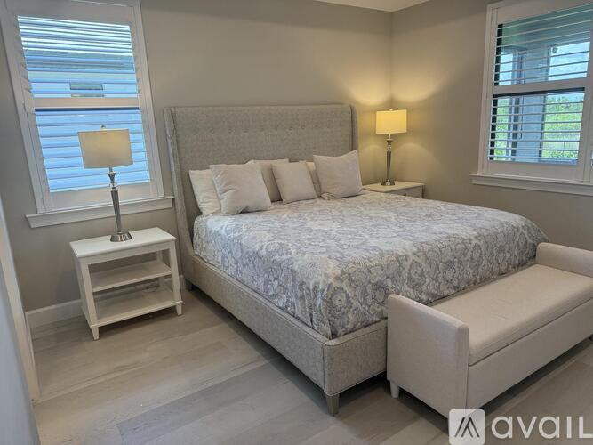 A bedroom with a large bed, a bench, and two lamps.