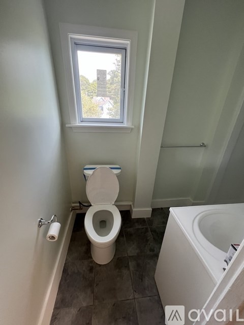 A bathroom with a toilet, a window, and a sink.
