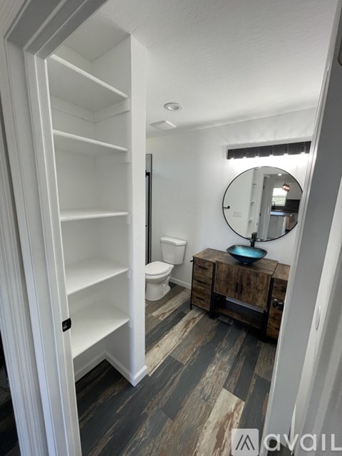 A bathroom with a white cabinet and a round mirror.