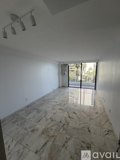 A spacious room with marble flooring and a large window.