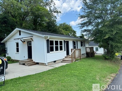 A white house with a black door and windows is for sale.