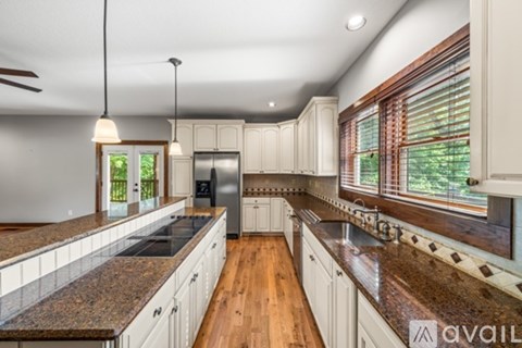 A kitchen with white cabinets and a granite countertop is available for rent.