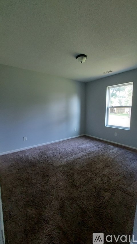 A spacious living room with a kitchen area in the background.