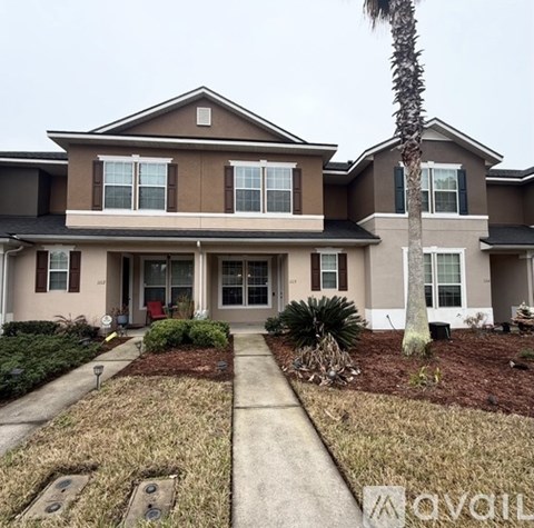 A house with a brown and beige exterior and a palm tree in front.