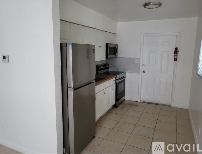 A kitchen with white cabinets and a stainless steel refrigerator.