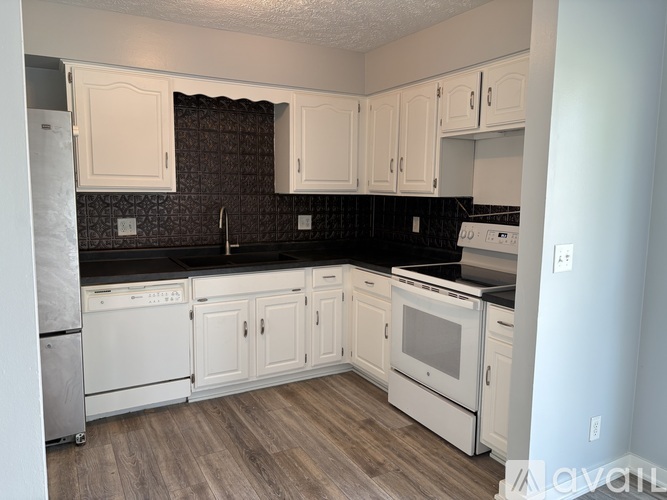A kitchen with white cabinets and black countertops.