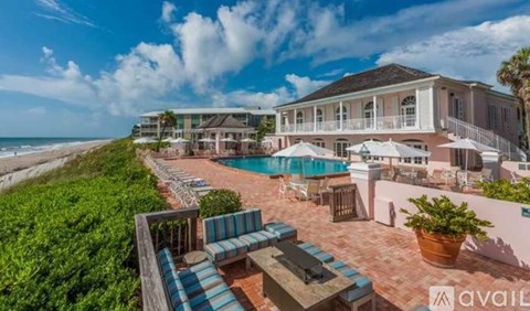 A large house with a pool and beach in the background.