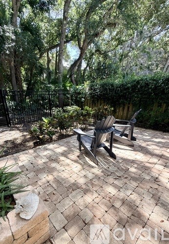 A patio with a bench and a table surrounded by trees.