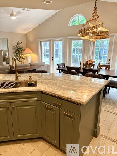 A kitchen with a marble countertop and green cabinets.
