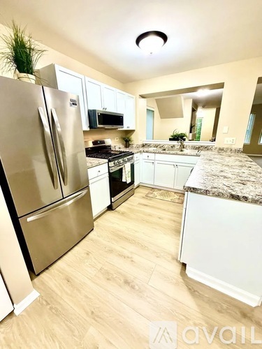 A kitchen with a stainless steel refrigerator and wooden flooring.