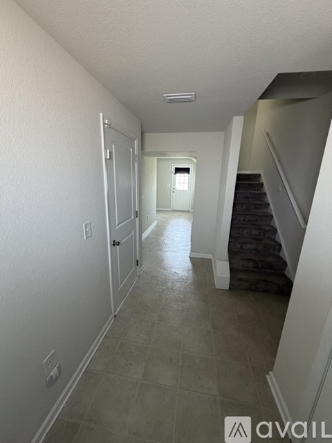 A hallway with a staircase on the right and a door on the left.