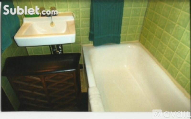 A white sink is mounted on a green wall above a black vanity.