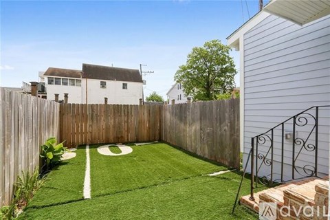 A backyard with a white line painted on the grass and a black metal gate.