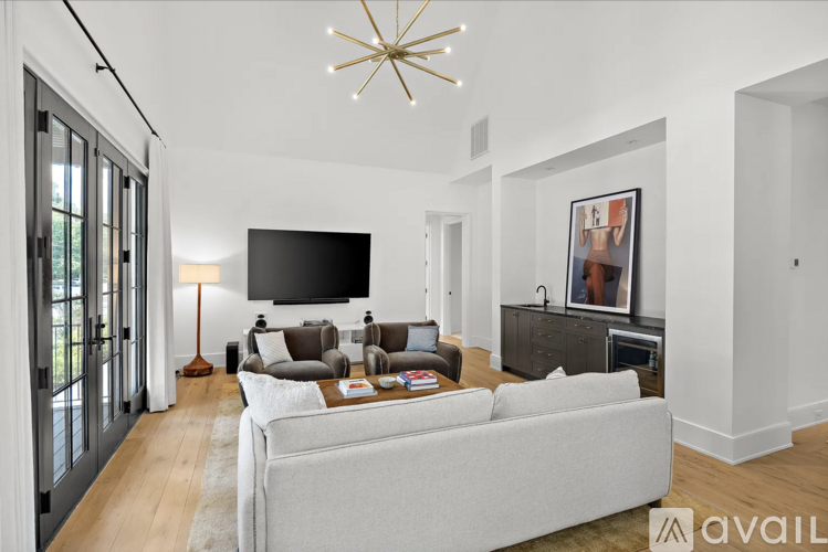 A living room with a grey couch and a chandelier.