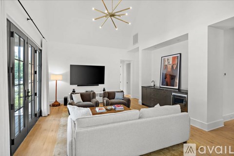 A living room with a grey couch and a chandelier.