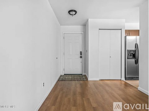 A kitchen area with a refrigerator, two doors, and a ceiling light.