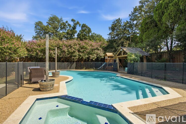 A pool surrounded by a fence and trees.