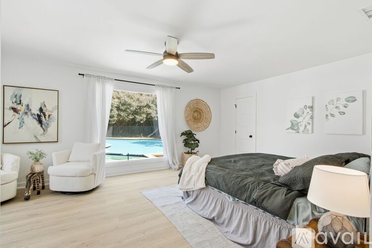A bedroom with a bed, chair, and a painting on the wall.