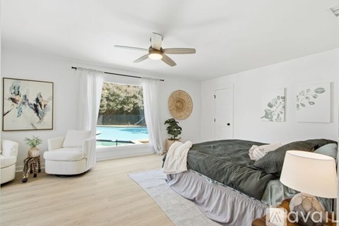 A bedroom with a bed, chair, and a painting on the wall.