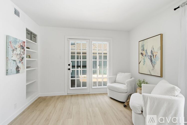 A living room with a white couch, a chair, and a painting on the wall.