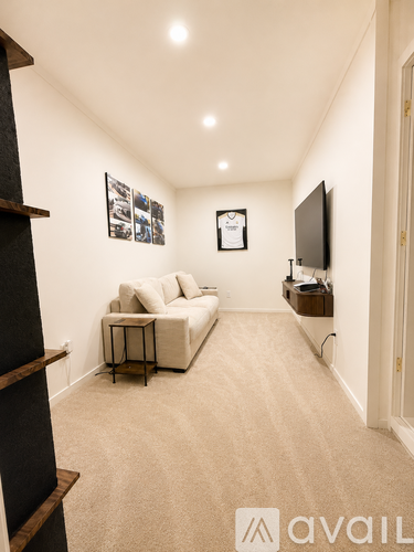 A living room with a white couch and a television on the wall.