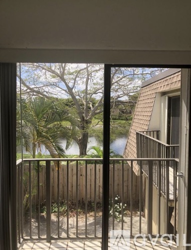 A view from a balcony looking out at a wooden fence and trees.