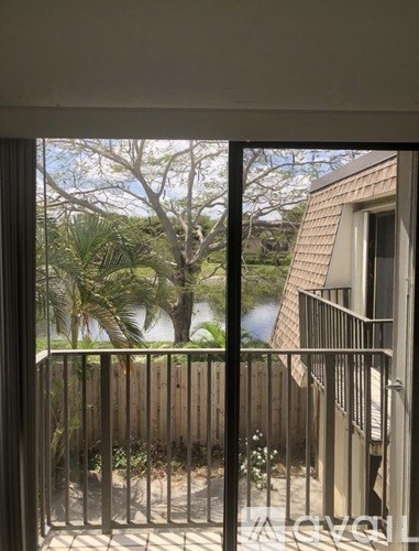 A view from a balcony looking out at a wooden fence and trees.