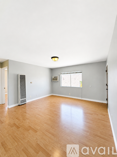 A spacious room with wooden flooring and a window.