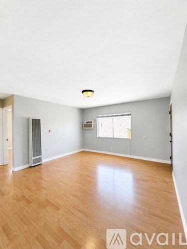 A spacious room with wooden flooring and a window.